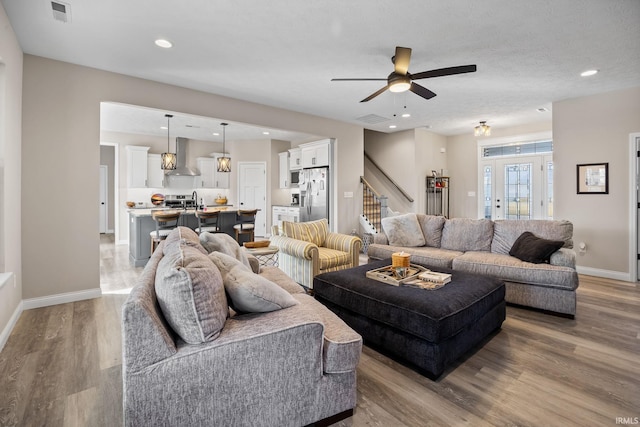 living area with stairway, wood finished floors, visible vents, baseboards, and recessed lighting