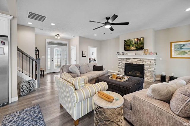 living room with visible vents, baseboards, stairs, a fireplace, and wood finished floors