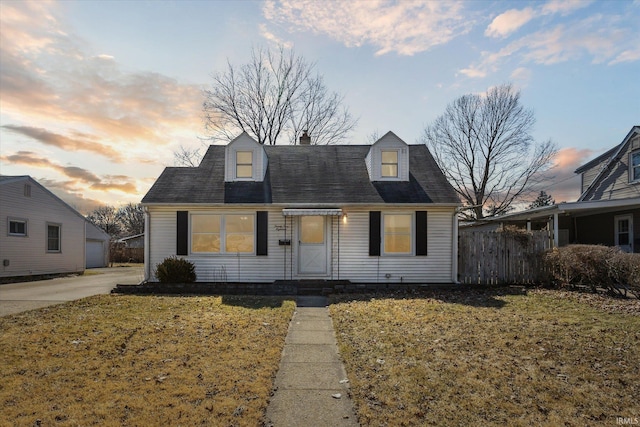 new england style home featuring fence, a yard, an outdoor structure, a garage, and a chimney