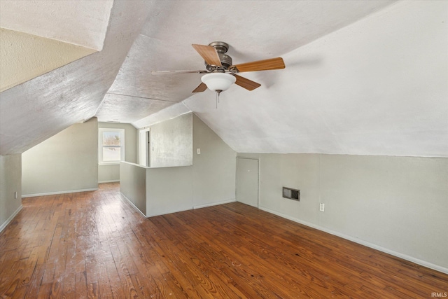 additional living space with baseboards, visible vents, lofted ceiling, wood-type flooring, and a textured ceiling