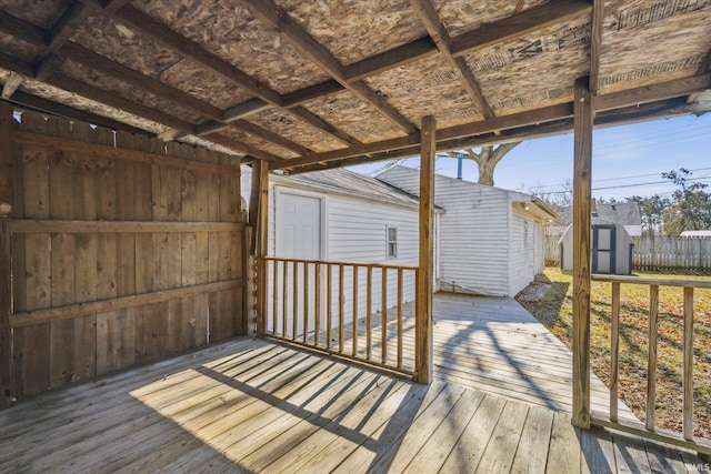 deck with a storage shed, an outbuilding, and fence