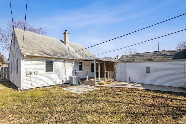 rear view of house with a yard, an outbuilding, a chimney, and fence