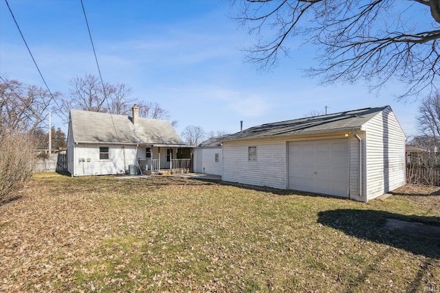 rear view of property featuring a detached garage, a lawn, a chimney, an outbuilding, and driveway