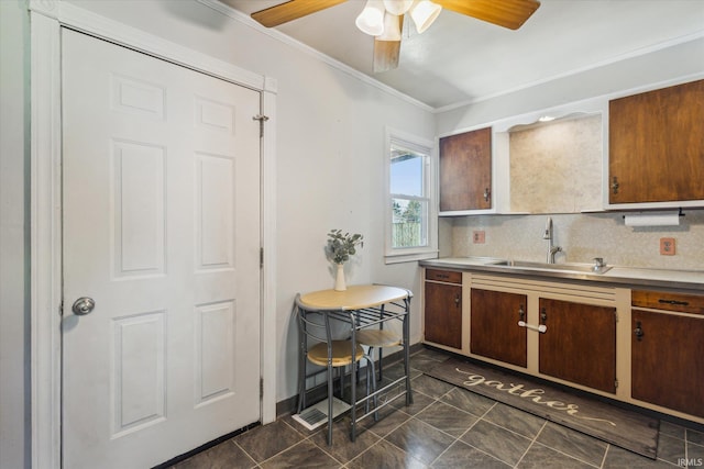 kitchen featuring dark tile patterned floors, ornamental molding, a sink, light countertops, and decorative backsplash