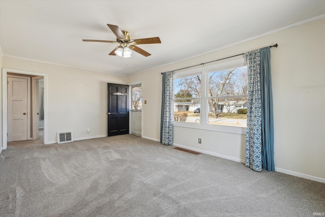 carpeted spare room featuring visible vents, ceiling fan, crown molding, and baseboards