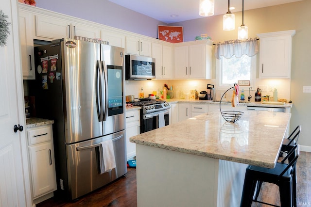 kitchen featuring light stone counters, a kitchen island, stainless steel appliances, white cabinets, and backsplash