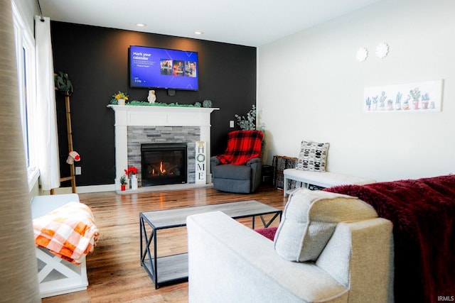 living area featuring a stone fireplace, recessed lighting, wood finished floors, and baseboards