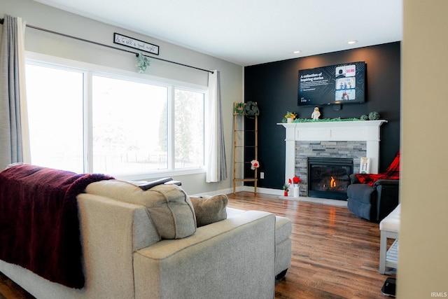 living area with recessed lighting, baseboards, a stone fireplace, and wood finished floors