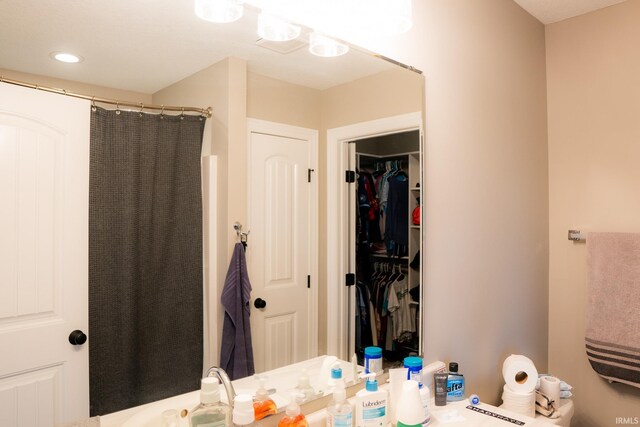 bathroom featuring a spacious closet and a shower with curtain