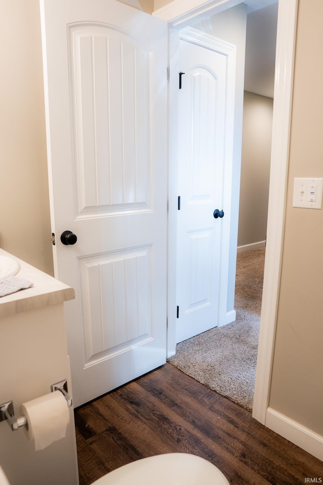 bathroom with vanity, toilet, wood finished floors, and baseboards