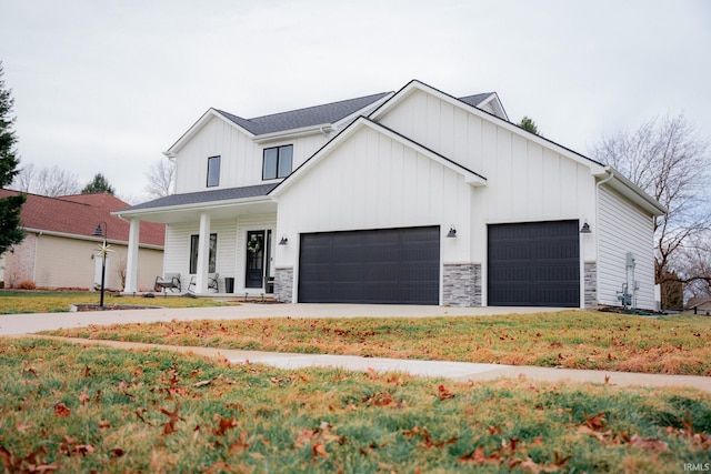 modern farmhouse featuring a front lawn, stone siding, a porch, board and batten siding, and concrete driveway