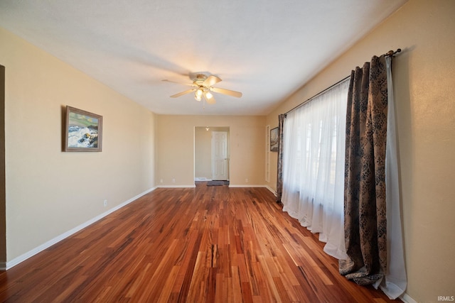 empty room with ceiling fan, baseboards, and wood finished floors