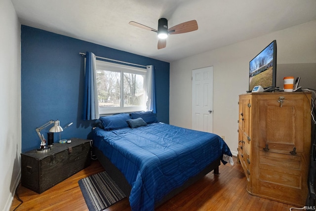 bedroom featuring light wood-style flooring, a ceiling fan, and baseboards