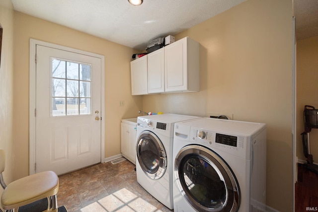 washroom featuring washer and dryer, baseboards, and cabinet space