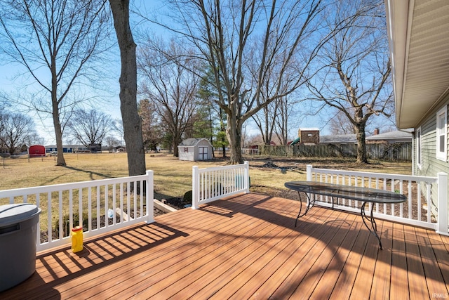 wooden deck with an outbuilding, a storage shed, a lawn, and fence