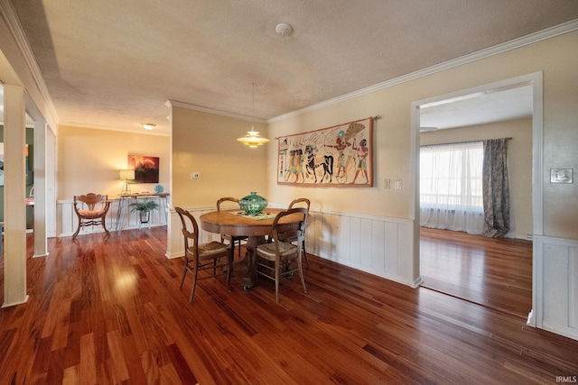 dining area featuring crown molding, wood finished floors, a wainscoted wall, and a textured ceiling