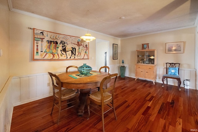 dining space with a textured ceiling, ornamental molding, wood finished floors, and wainscoting