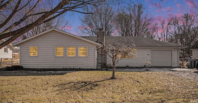 view of front facade with driveway, a chimney, and an attached garage