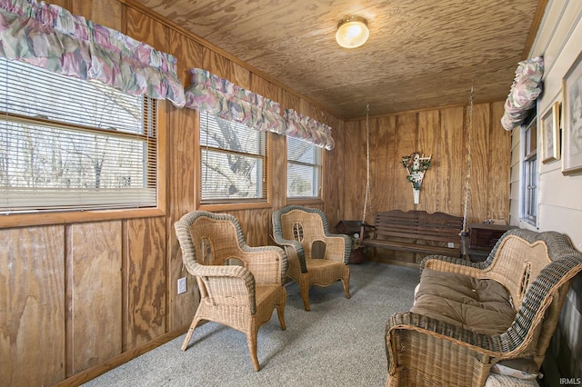 sitting room featuring plenty of natural light, wood walls, and carpet