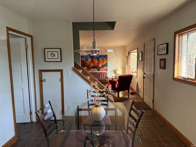 dining space featuring baseboards and dark tile patterned flooring