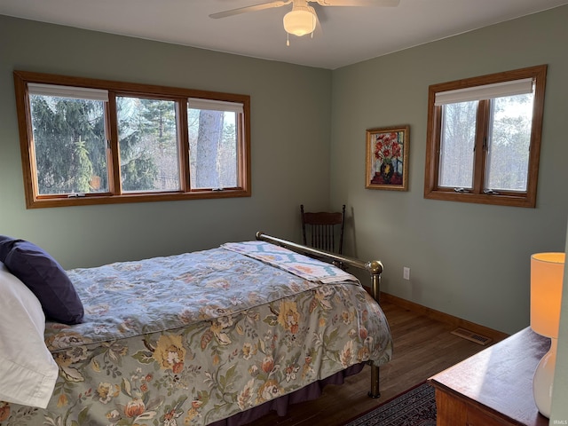 bedroom with ceiling fan, wood finished floors, visible vents, and baseboards