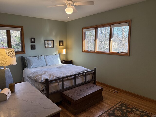 bedroom with visible vents, multiple windows, baseboards, and wood finished floors