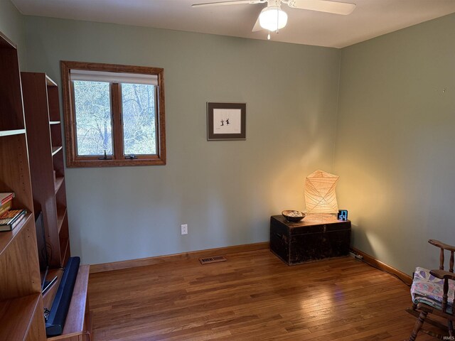 interior space featuring hardwood / wood-style floors, baseboards, visible vents, and a ceiling fan