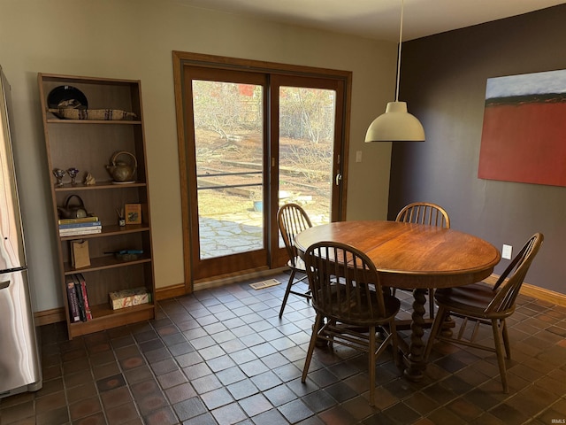 dining area featuring dark tile patterned floors and baseboards