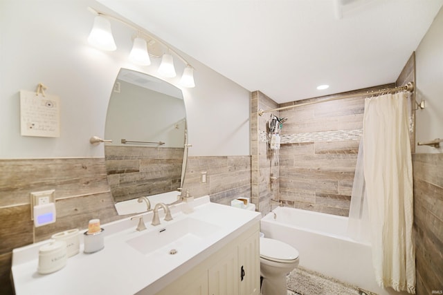 bathroom with tile walls, toilet, shower / bath combo with shower curtain, wainscoting, and vanity