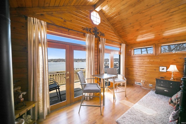 interior space featuring wooden walls, light wood finished floors, lofted ceiling with beams, wood ceiling, and french doors