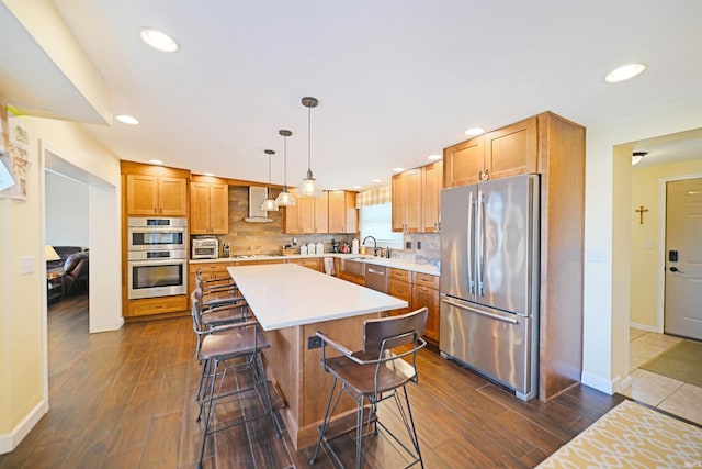 kitchen with a kitchen bar, a sink, backsplash, appliances with stainless steel finishes, and light countertops