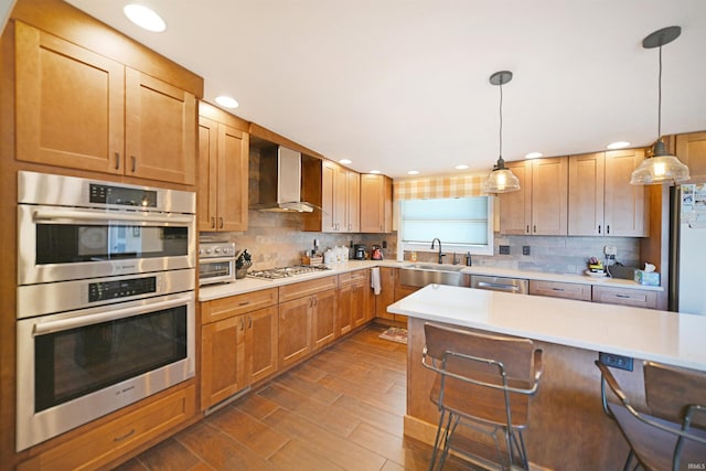 kitchen with a sink, wall chimney range hood, stainless steel appliances, light countertops, and decorative backsplash