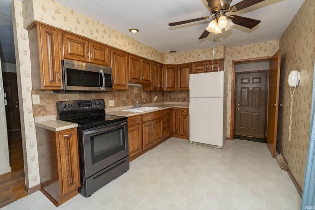 kitchen featuring brown cabinets, appliances with stainless steel finishes, wallpapered walls, and light countertops