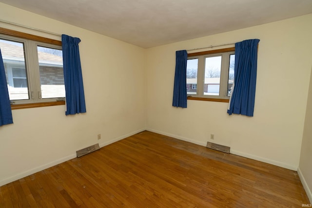 spare room with visible vents, baseboards, and wood finished floors