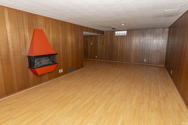 empty room with visible vents, wooden walls, and wood finished floors