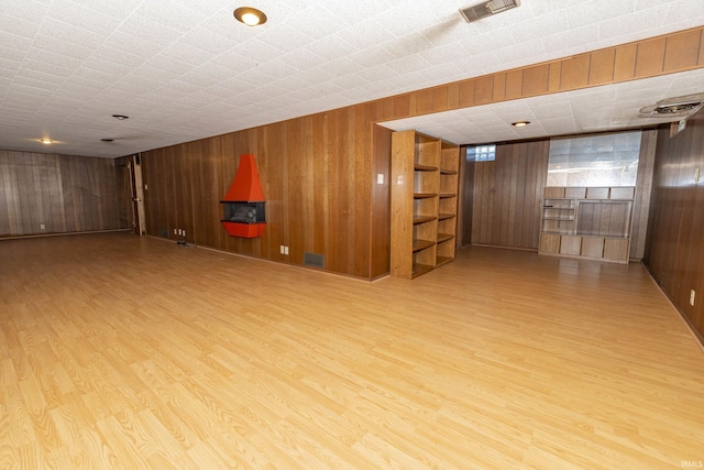 interior space featuring visible vents, wooden walls, and wood finished floors