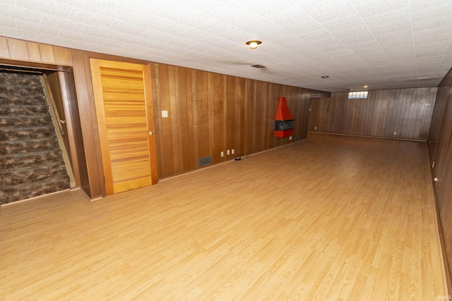 finished below grade area featuring visible vents, wood walls, and wood finished floors