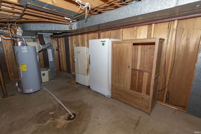 unfinished below grade area with gas water heater, heating unit, refrigerator, and freestanding refrigerator