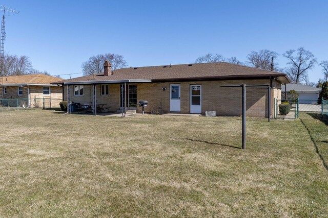 back of property with brick siding, a lawn, and fence