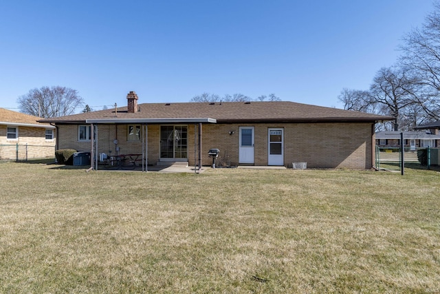 back of property featuring fence, brick siding, a chimney, a patio area, and a lawn