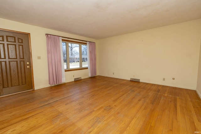 empty room featuring visible vents and light wood-type flooring