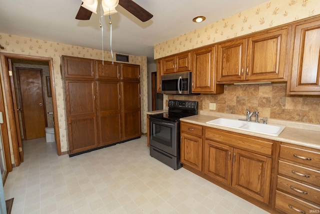 kitchen with visible vents, wallpapered walls, a sink, stainless steel appliances, and brown cabinets