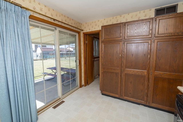 doorway to outside featuring visible vents, light floors, and wallpapered walls