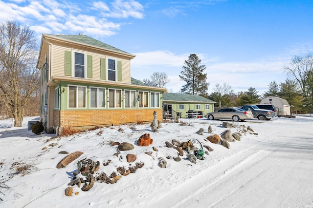 snow covered back of property featuring brick siding