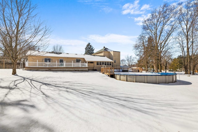 snow covered house with an outdoor pool and a deck