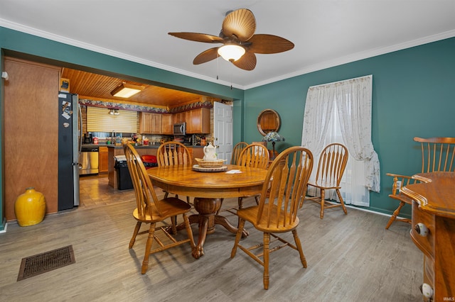 dining room featuring crown molding, baseboards, visible vents, and light wood finished floors