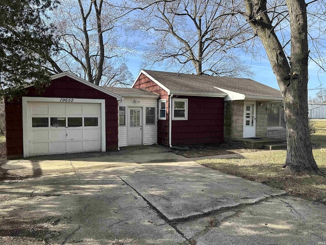 view of front facade featuring stone siding, an attached garage, driveway, and a shingled roof