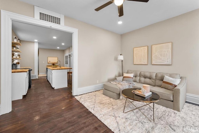 living area with ceiling fan, visible vents, baseboards, and dark wood finished floors