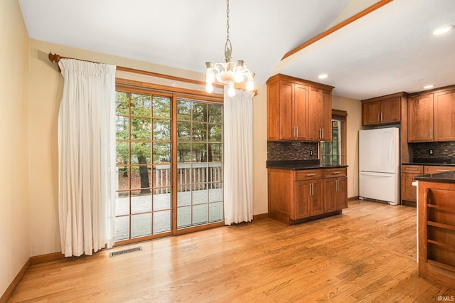 kitchen with dark countertops, visible vents, backsplash, light wood finished floors, and freestanding refrigerator