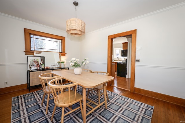 dining space featuring baseboards, dark wood finished floors, and crown molding